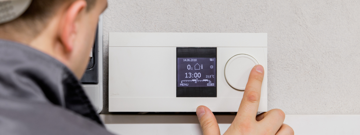 Technician adjusting a digital thermostat on the wall, setting temperature and time controls for optimal climate management. The image highlights professional HVAC service, energy efficiency, and home comfort solutions.