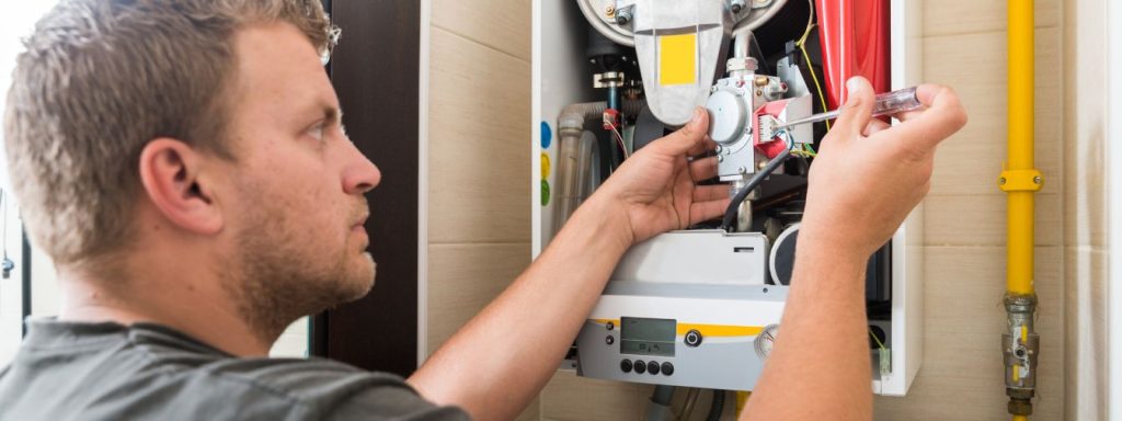 An HVAC technician carefully examines and adjusts a component inside a gas furnace, emphasizing the importance of professional inspections to ensure safe, efficient, and reliable heating system performance.